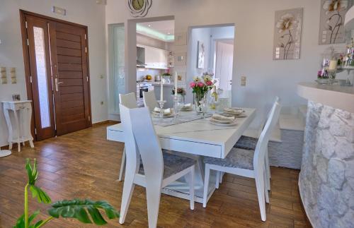 圣斯特凡诺斯Elena Luxury Suite Agios Stefanos的白色的用餐室配有白色的桌椅