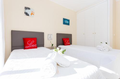 波尔蒂芒Love Sun Beach Apartment的宿舍间内的两张床,配有红色枕头