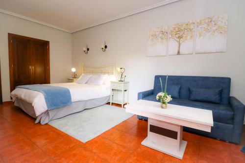 阿雷纳斯德圣佩德罗Hotel Rural El Retiro de San Pedro by RetiroRural的一间卧室配有一张床和一张蓝色的沙发
