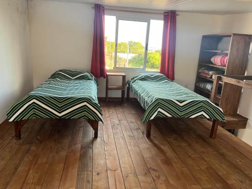 德尔迪阿布罗角Hyepy的客房内设有两张床,铺有木地板,设有窗户。