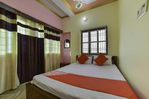 BihtaOYO Flagship Ashoka Guest House的一间卧室配有一张带橙色枕头的大床