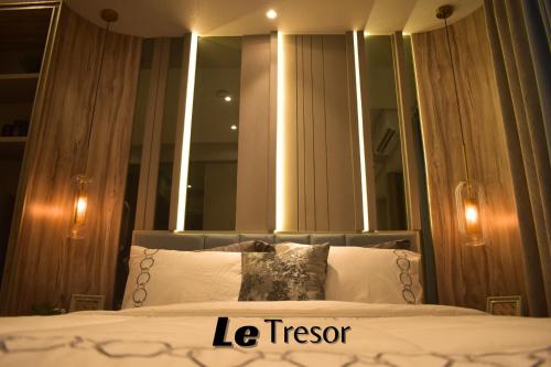 泗水Le Tresor Benson Apartment at Supermal Pakuwon的一间卧室配有一张带大镜子的床