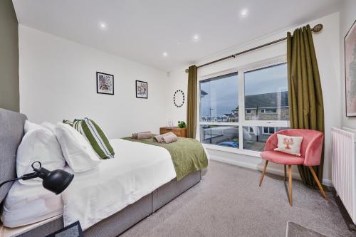 斯图尔特港Portstewart Central Loft Apartment的一间卧室设有一张床、一个窗口和一把椅子