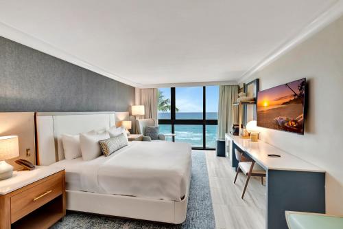 棕榈滩Tideline Palm Beach Ocean Resort and Spa的酒店客房设有一张大床、一张书桌和一张书桌。