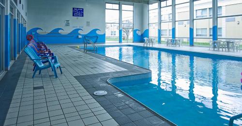 伦敦伦敦华美达酒店的一座大楼内带蓝色长椅的游泳池