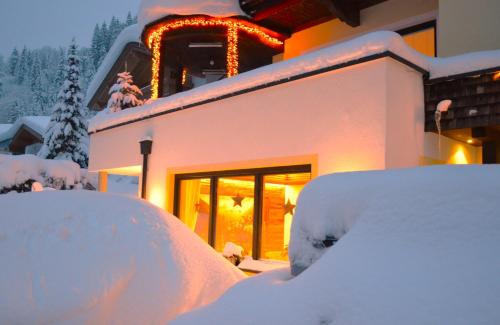 盖洛斯Pension Zillertal的一座建筑物前的雪覆盖的房子