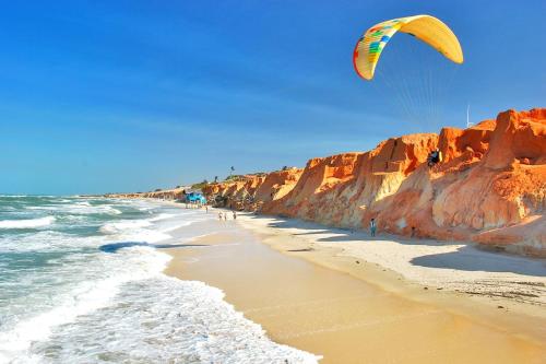 福塔莱萨Premium Flats - Praia Mansa的一个人在海滩上玩风筝