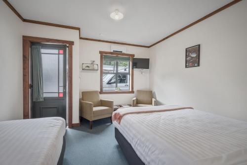 普纳凯基Punakaiki Rocks Hotel & Garden Bar的酒店客房,配有两张床和椅子