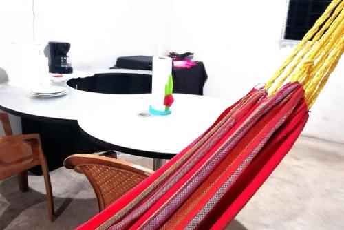 拉利伯塔德COSTA AZUL Apartment的一张桌子和椅子,配有红色和黄色的吊床