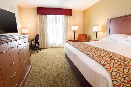 丹佛Drury Inn and Suites Denver Central Park的配有一张床和一台平面电视的酒店客房