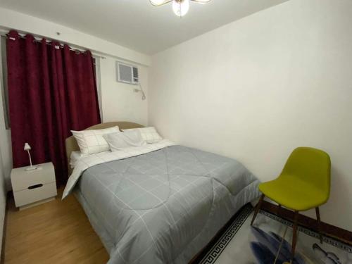 达沃市Arezzo Place Davao Condominium的一间卧室配有一张床和一把绿色椅子