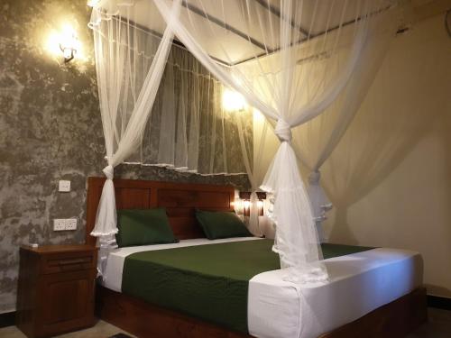 代尼耶耶Rain Forest Star的一间卧室配有一张带绿床单的天蓬床
