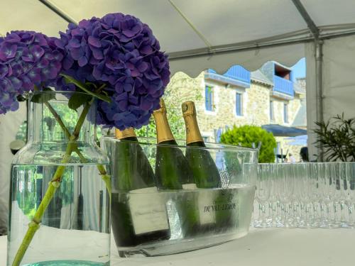 朗巴勒Logis Hôtel Le Manoir Des Portes的装满葡萄酒瓶和紫色鲜花的花瓶
