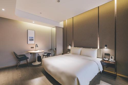上海上海北外滩亚朵酒店的酒店客房设有一张白色大床和一张桌子。
