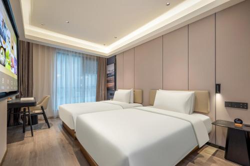 上海上海虹桥莘庄商务区亚朵酒店的酒店客房设有两张床和一台平面电视。