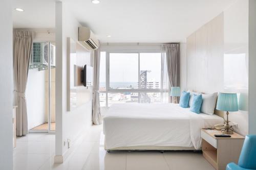 华欣华欣皇家馆酒店的白色的卧室设有一张大床和一个窗户