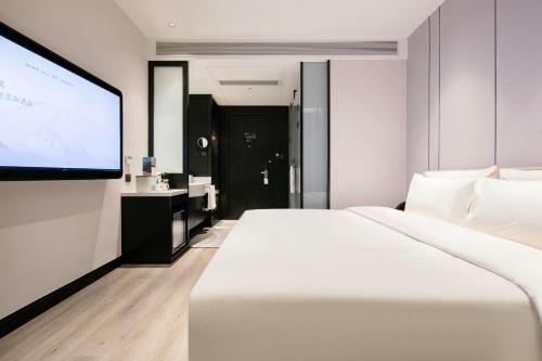 杭州杭州西湖武林广场延安路亚朵X酒店的酒店客房设有一张白色大床和投影屏幕