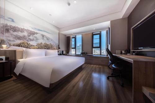 昆明昆明滇池亚朵酒店的卧室配有一张白色大床和一张书桌