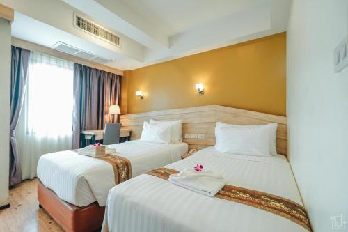 那空拍侬府Porpiang Hotel - โรงแรมพอเพียง的酒店客房配有两张床和一张书桌