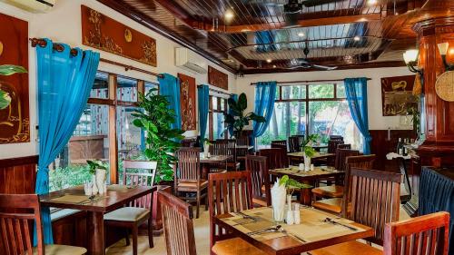 暹粒Harmony Indochine d'Angkor的餐厅设有木桌和椅子以及蓝色窗帘