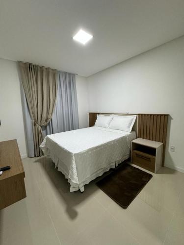 伊塔佩马Apartamento à 390m do Mar的卧室配有白色的床和窗户。