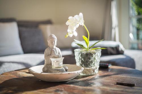 曼克玛肖Heide Hues的一张带雕像的桌子和一个带花的花瓶