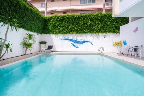 华欣华欣皇家馆酒店的一座游泳池,旁边是白色的植物墙
