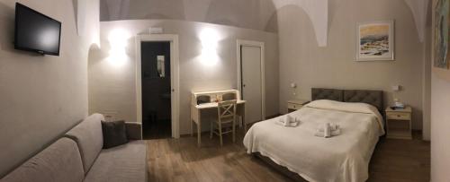 BovinoResidenza la Portella的一间卧室配有一张床、一张沙发和一台电视