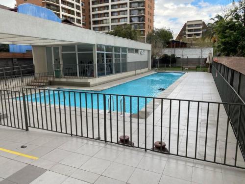 圣地亚哥Ñuñoa, Bello departamento, La mejor ubicacion的建筑物围栏后面的游泳池