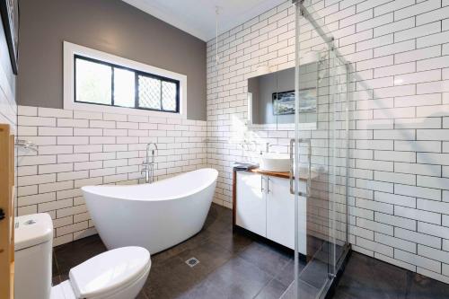 Kin Kinkin kin cottage, Noosa hinterland, walk to town.的白色的浴室设有浴缸和卫生间。