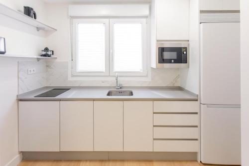 马拉加Nosquera FreshApartaments by Bossh! Apartaments的白色的厨房配有水槽和微波炉