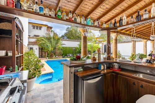 IlloraCasa de Amigos La Latina con chimenea y barbacoa的室外厨房的背景是游泳池