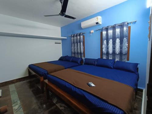 蒂鲁瓦纳马莱Agnisthala Guest House的一间卧室设有两张床和蓝色的墙壁