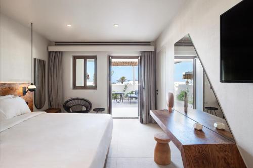 梅萨雷亚Noūs Santorini的酒店客房设有一张床和一张书桌,享有美景。