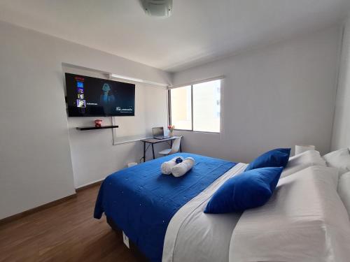 利马Habitacion baño Propio La Paz 1的一间卧室配有一张带蓝色枕头的床和一台电视。
