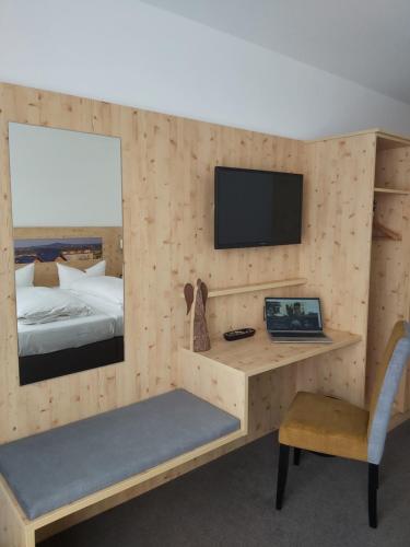 黑伯廷根恩格尔餐厅酒店的一间卧室配有一张桌子和一张带电视的床。
