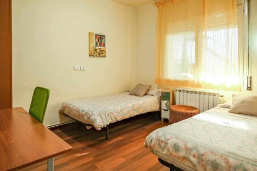 贝萨卢Can Camps Besalú Alojamiento con jardín privado的一间卧室设有两张床、一张桌子和一个窗口