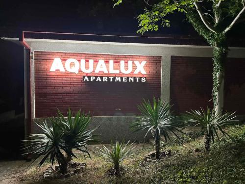 斯塔多伊兰Aqualux Apartments的前面有植物的建筑上的标志