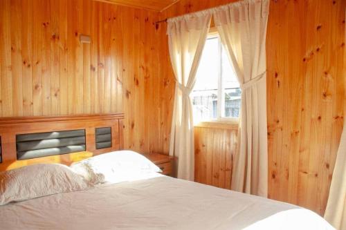 安库德CABAÑAS LAS DALIAS ANCUD的一间卧室配有一张带木墙和窗户的床。