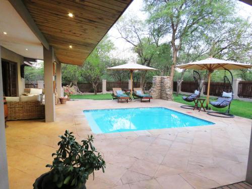 侯斯普瑞特Wild Dog Guest Lodge的一个带两把遮阳伞的游泳池和一个庭院