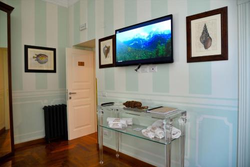 安齐奥Regal House Anzio Manetti 16的一间墙上的电视机,玻璃桌