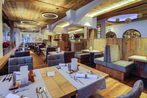 贝希特斯加登Alpenhotel Fischer 4 Sterne - Adults Only的餐厅铺有木地板,配有桌椅