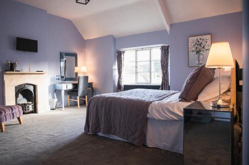 WedmoreThe George Inn Wedmore的一间卧室设有紫色的墙壁和一张带壁炉的床。