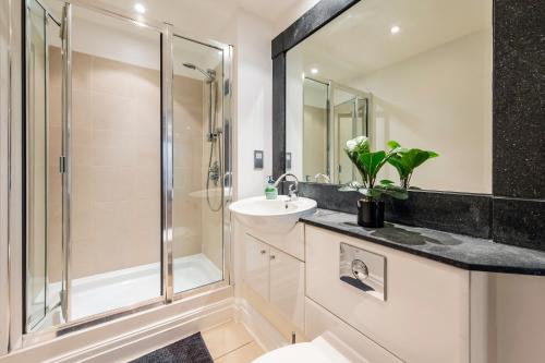 伦敦Modern Paddington Station 2 Bedroom Apartment的一间带玻璃淋浴和水槽的浴室