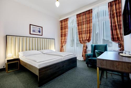 玛丽亚温泉马克西姆酒店的一间卧室配有一张床、一张桌子和一把椅子