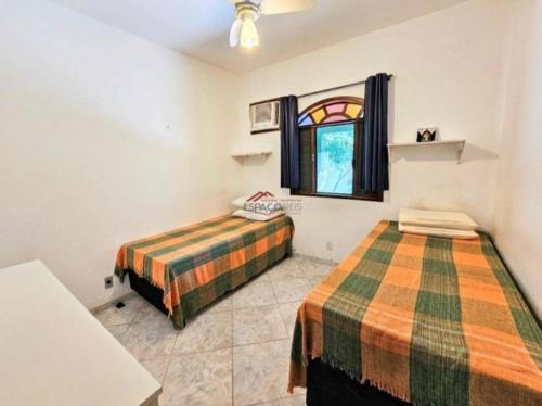 考卡亚Casa de praia的一间卧室设有两张床,其中设有窗户。