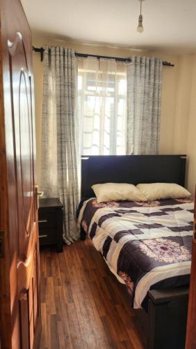 ThikaDelight Stays的一间卧室配有床和带窗帘的窗户