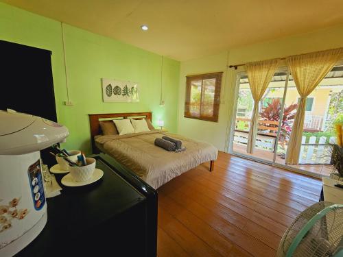 象岛Baan suan khun ta บ้านพักสวนคุณตา的一间设有床铺的卧室,位于一个拥有绿色墙壁的房间