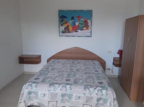 圣尼科拉Perla Marina的卧室内的一张床铺,墙上有绘画作品