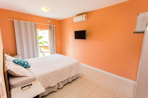 卡姆布库Panorama Cumbuco的一间卧室设有橙色的墙壁、一张床和电视